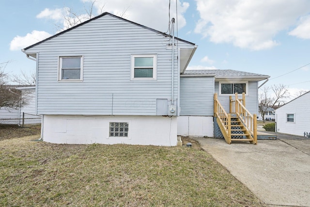 rear view of house with a lawn and fence