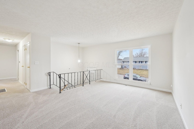 carpeted empty room featuring visible vents, baseboards, and a textured ceiling