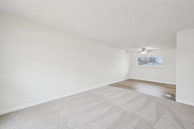 carpeted spare room featuring baseboards, a textured ceiling, and ceiling fan