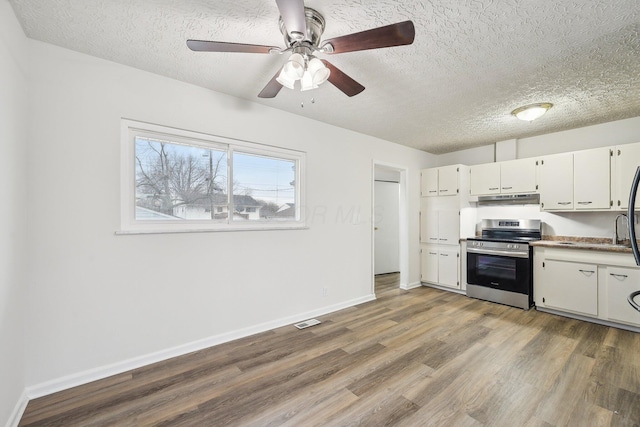 kitchen with visible vents, under cabinet range hood, stainless steel electric stove, wood finished floors, and white cabinetry