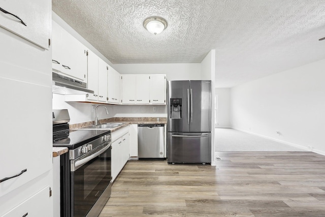 kitchen featuring under cabinet range hood, light wood-type flooring, white cabinets, stainless steel appliances, and a sink