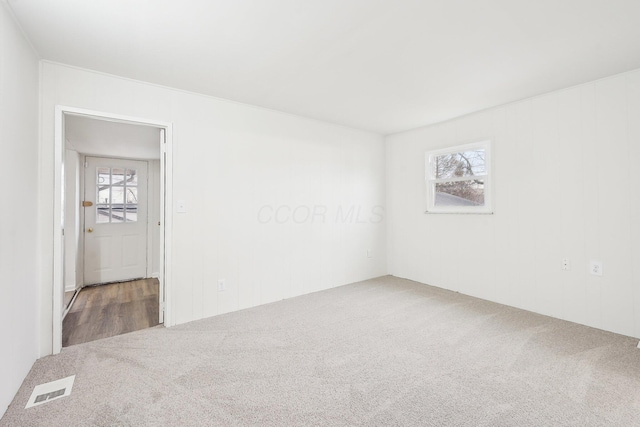 carpeted spare room featuring a healthy amount of sunlight and visible vents