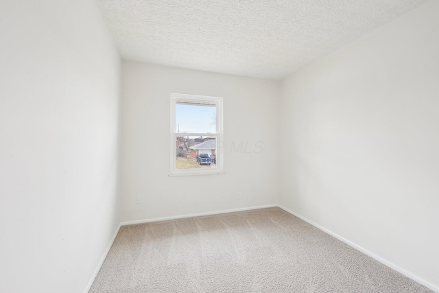 empty room featuring baseboards, carpet, and a textured ceiling