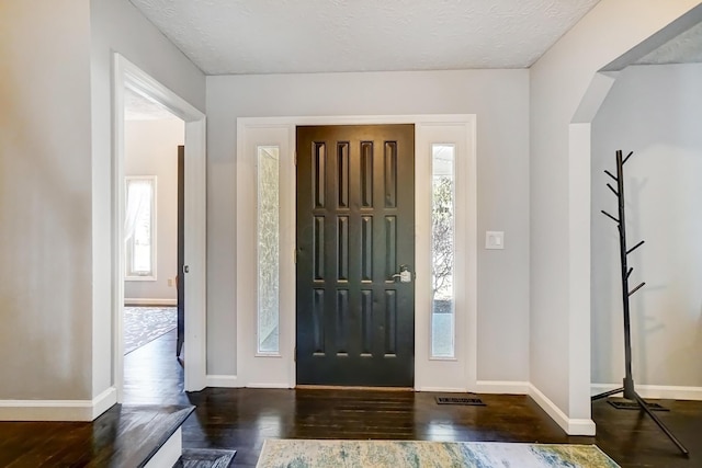 entrance foyer with plenty of natural light, a textured ceiling, baseboards, and wood finished floors