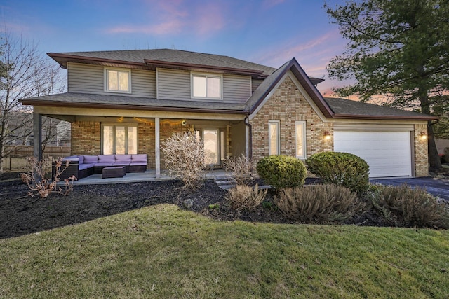 view of front of house with outdoor lounge area, a garage, a lawn, and brick siding