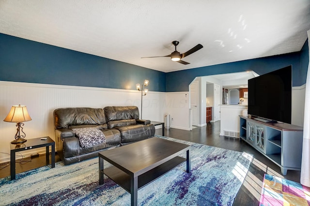 living area featuring wainscoting, wood finished floors, visible vents, and ceiling fan