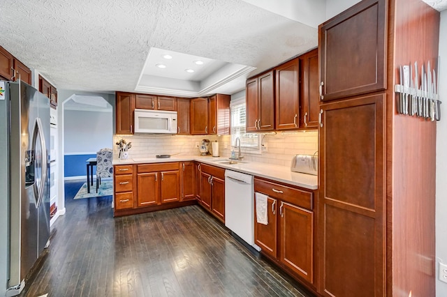 kitchen with white appliances, dark wood-style flooring, a sink, light countertops, and a raised ceiling