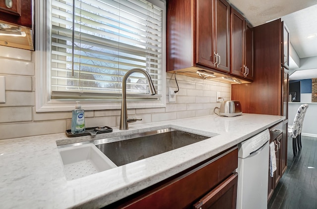 kitchen with a sink, tasteful backsplash, dark wood-style floors, light stone countertops, and dishwasher