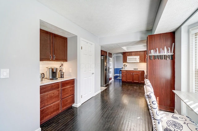 kitchen with dark wood finished floors, light countertops, stainless steel fridge with ice dispenser, and white microwave