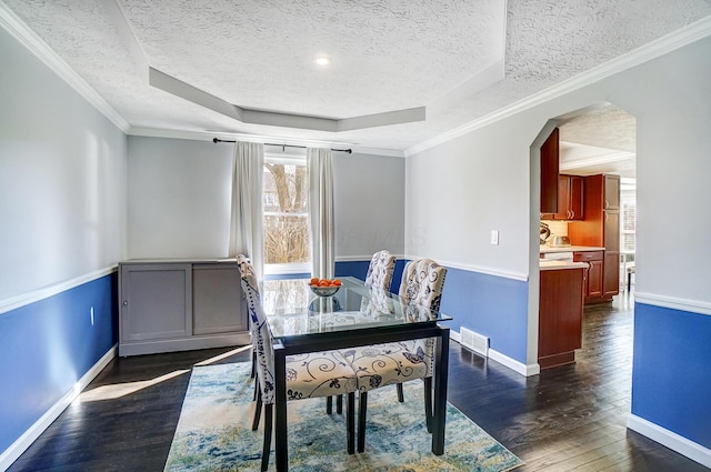 dining area featuring visible vents, baseboards, arched walkways, a raised ceiling, and dark wood-style flooring