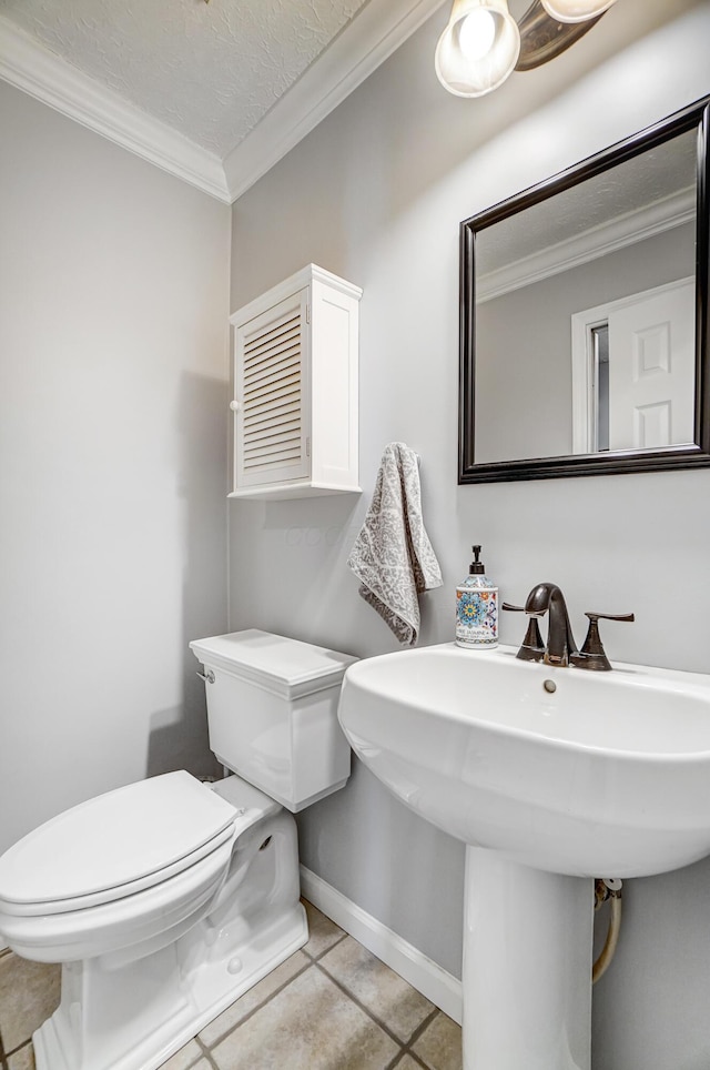 bathroom with tile patterned flooring, toilet, crown molding, and baseboards