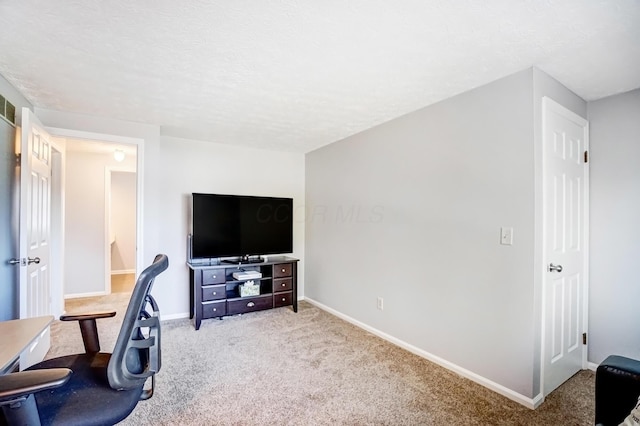 carpeted office space with a textured ceiling and baseboards