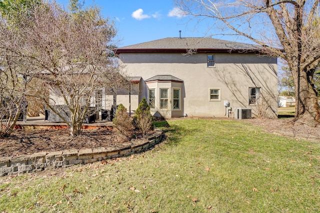 rear view of property featuring stucco siding, a lawn, and cooling unit