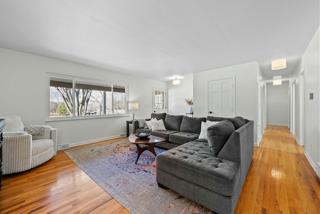 living area featuring light wood finished floors, visible vents, and baseboards