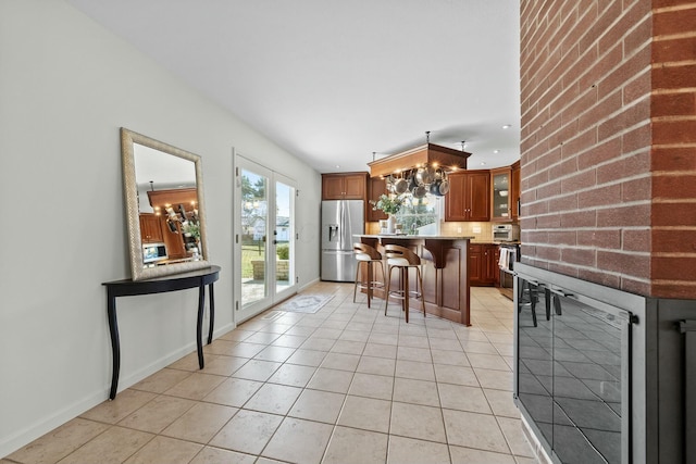 kitchen with wine cooler, a breakfast bar, light tile patterned floors, decorative backsplash, and stainless steel fridge