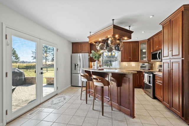 kitchen featuring backsplash, a kitchen island, a breakfast bar area, french doors, and stainless steel appliances