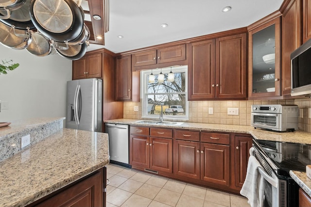 kitchen with backsplash, light stone countertops, appliances with stainless steel finishes, and a sink