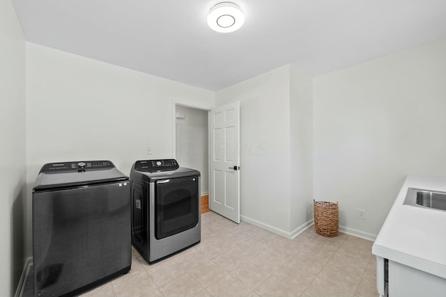 clothes washing area with a sink, baseboards, laundry area, and washing machine and clothes dryer