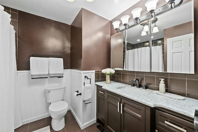 bathroom featuring tile patterned flooring, toilet, vanity, and a wainscoted wall