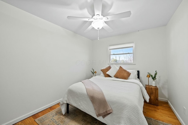 bedroom with ceiling fan, baseboards, and light wood-style flooring