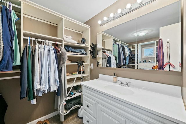 bathroom featuring a spacious closet, vanity, and baseboards