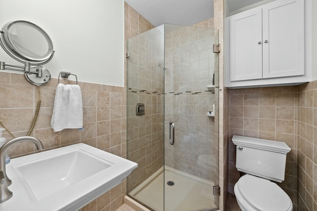 bathroom featuring a sink, toilet, tile walls, and a shower stall