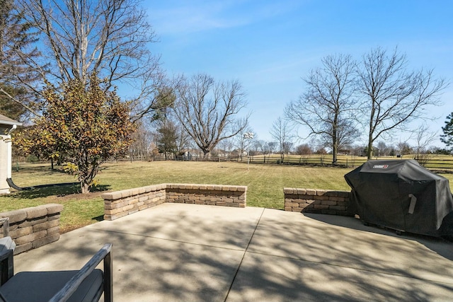 view of patio featuring a rural view, fence, and a grill