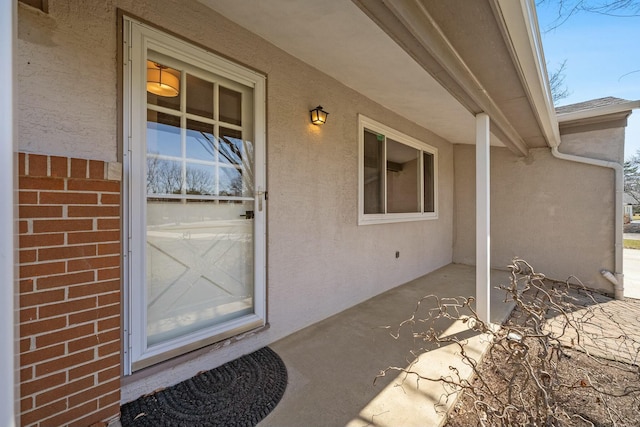 property entrance featuring stucco siding and brick siding