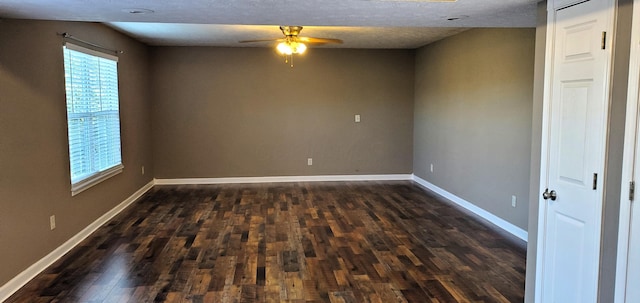 empty room with dark wood finished floors, a textured ceiling, a ceiling fan, and baseboards