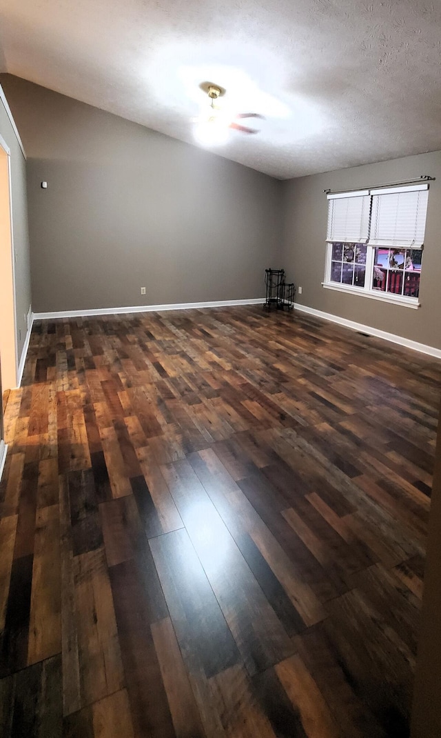 spare room featuring baseboards and dark wood-style flooring