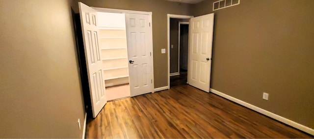 unfurnished bedroom featuring visible vents, baseboards, and dark wood-style flooring