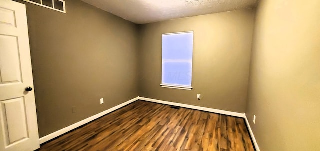 unfurnished room with baseboards, a textured ceiling, and dark wood-style floors