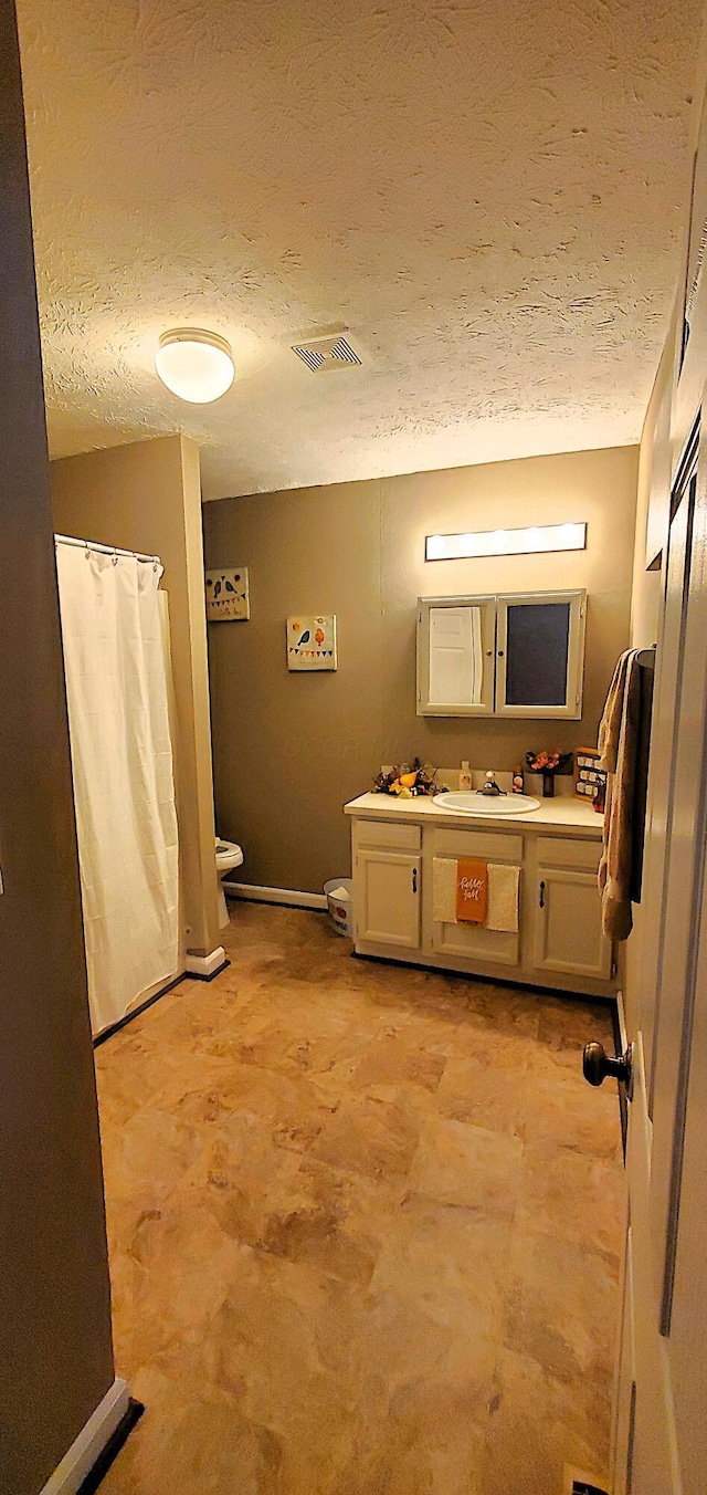 bathroom with visible vents, a textured ceiling, vanity, and toilet