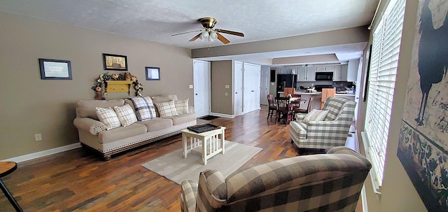 living room with dark wood finished floors, ceiling fan, a textured ceiling, and baseboards