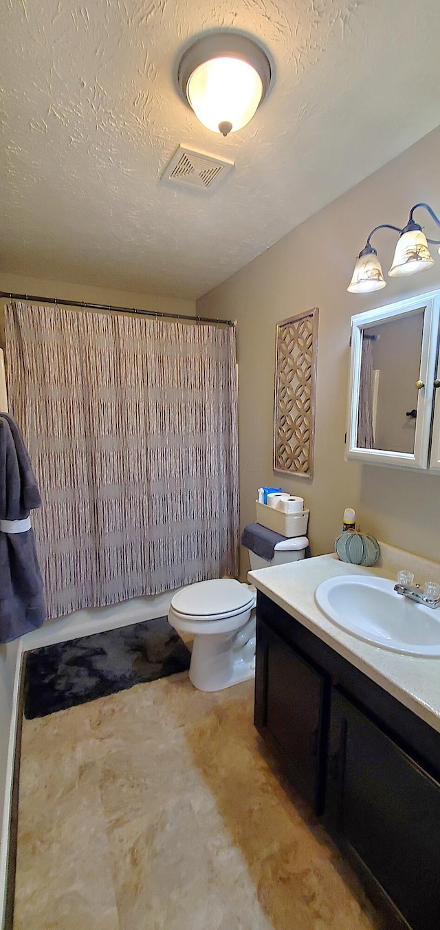 full bathroom featuring visible vents, a shower with curtain, toilet, a textured ceiling, and vanity