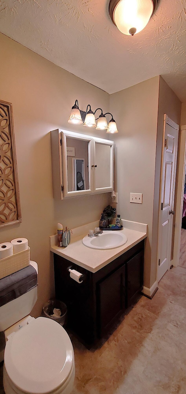 bathroom with toilet, a textured ceiling, and vanity