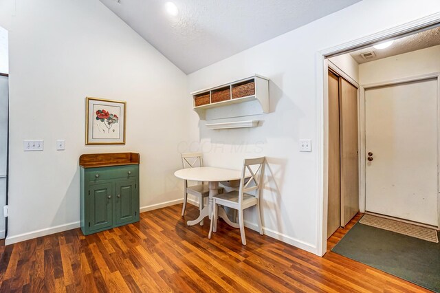 dining space featuring visible vents, baseboards, dark wood-type flooring, and vaulted ceiling