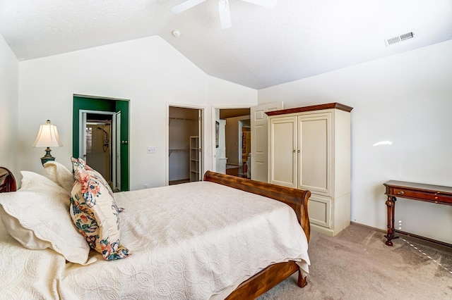 bedroom with visible vents, a walk in closet, light colored carpet, vaulted ceiling, and a ceiling fan