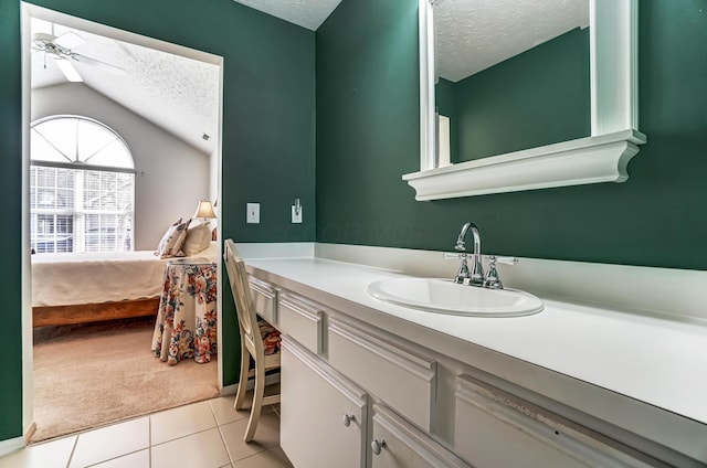 ensuite bathroom with tile patterned flooring, ceiling fan, vanity, lofted ceiling, and a textured ceiling