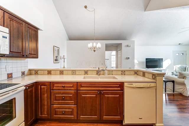 kitchen featuring white appliances, an inviting chandelier, a peninsula, a sink, and open floor plan