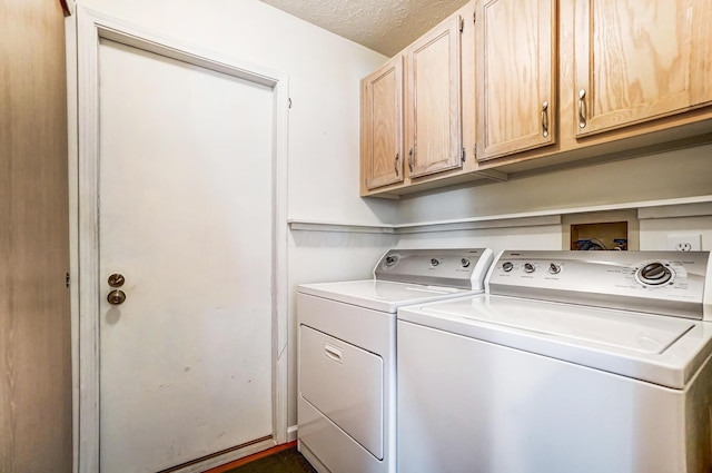 laundry area featuring cabinet space, a textured ceiling, and washer and clothes dryer