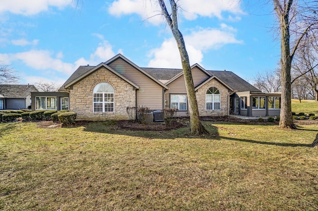 back of house featuring a yard, stone siding, central AC, and a sunroom