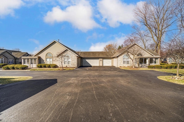 view of front of home featuring aphalt driveway, stone siding, and a garage