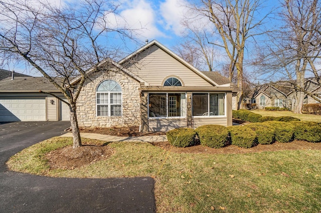 view of front of property with aphalt driveway, a garage, stone siding, and a front lawn