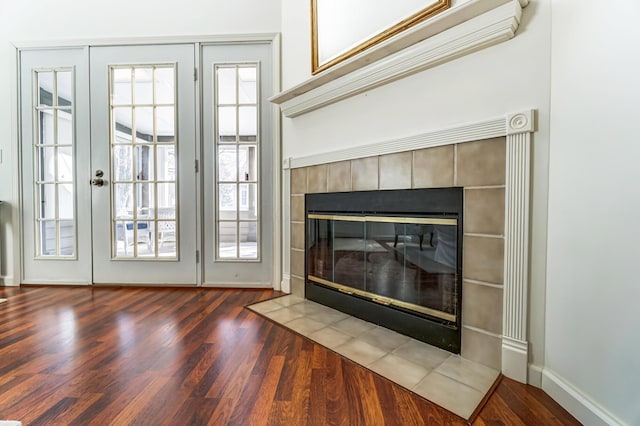 doorway to outside with a tile fireplace, baseboards, and wood finished floors