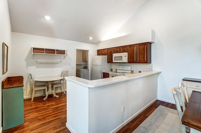 kitchen featuring tasteful backsplash, washing machine and dryer, light countertops, lofted ceiling, and white appliances