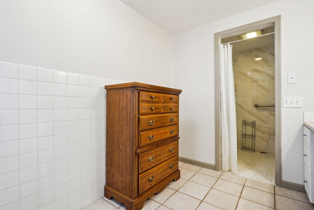 full bathroom with tile walls, a shower with shower curtain, tile patterned floors, a textured ceiling, and vanity