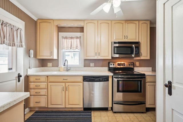 kitchen with light countertops, cream cabinets, stainless steel appliances, a ceiling fan, and a sink