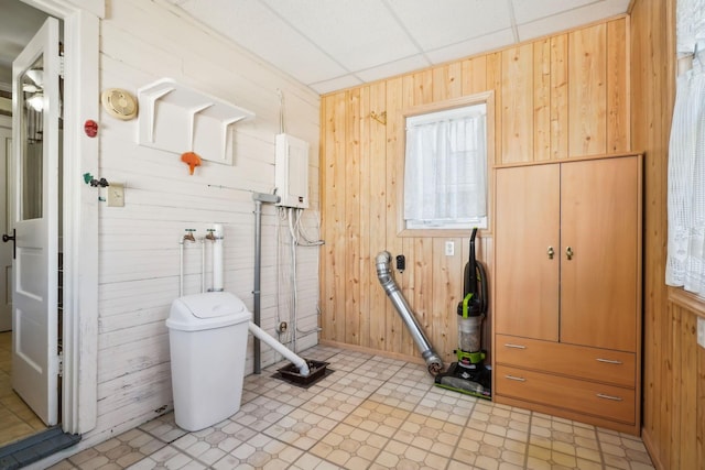 laundry area featuring laundry area, light floors, and wood walls