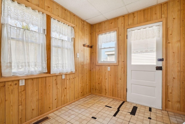 doorway featuring light floors, visible vents, wood walls, and baseboards